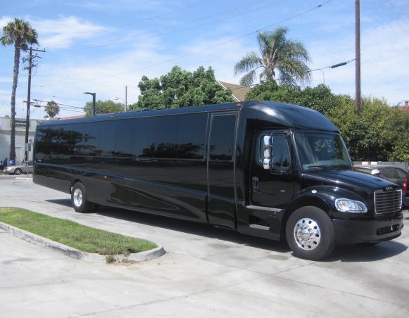 Black Freightliner-chassis 44-passenger executive bus parked on a lot, front three-quarter