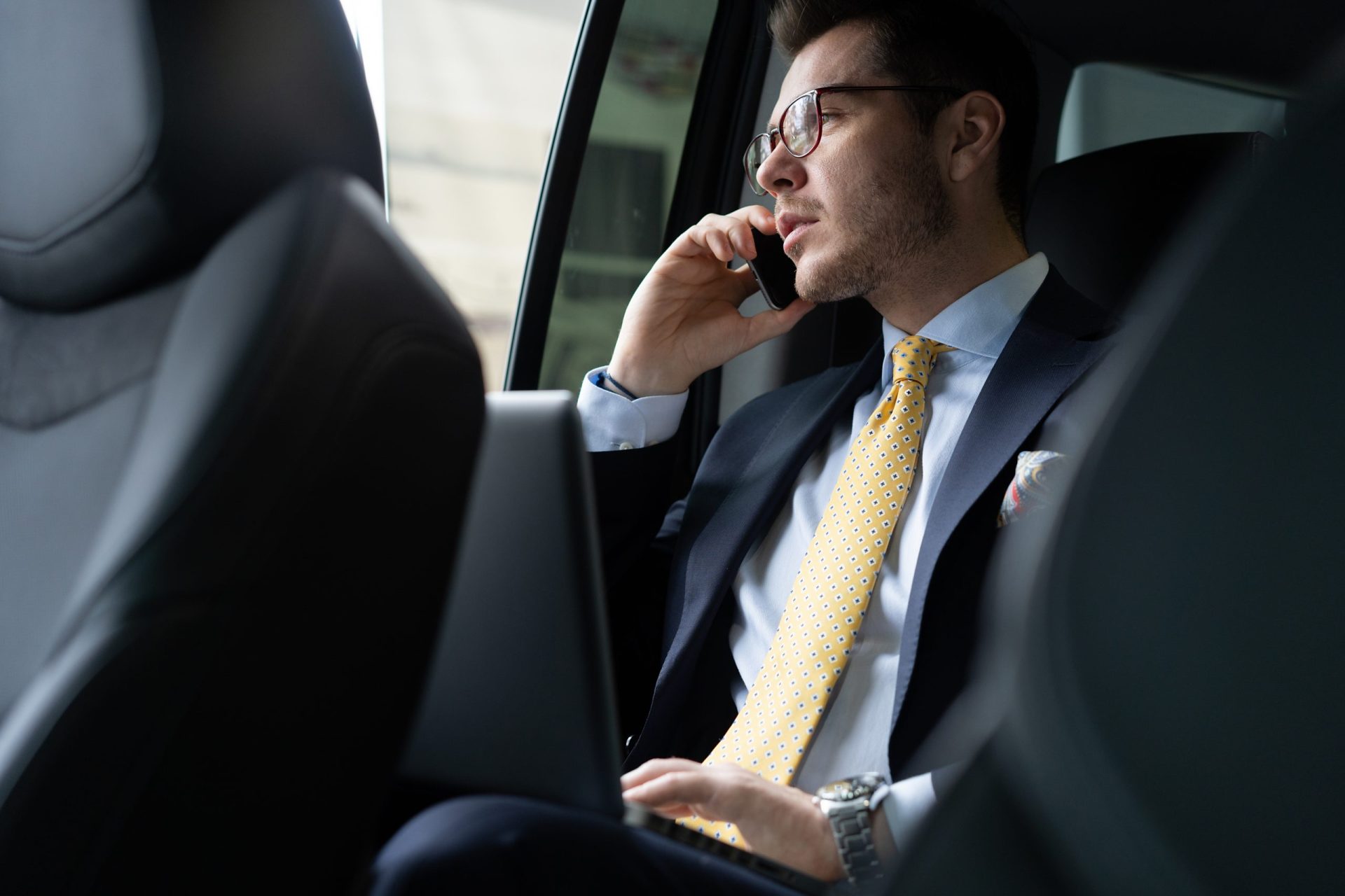 Passenger in the back seat of a chauffeured sedan